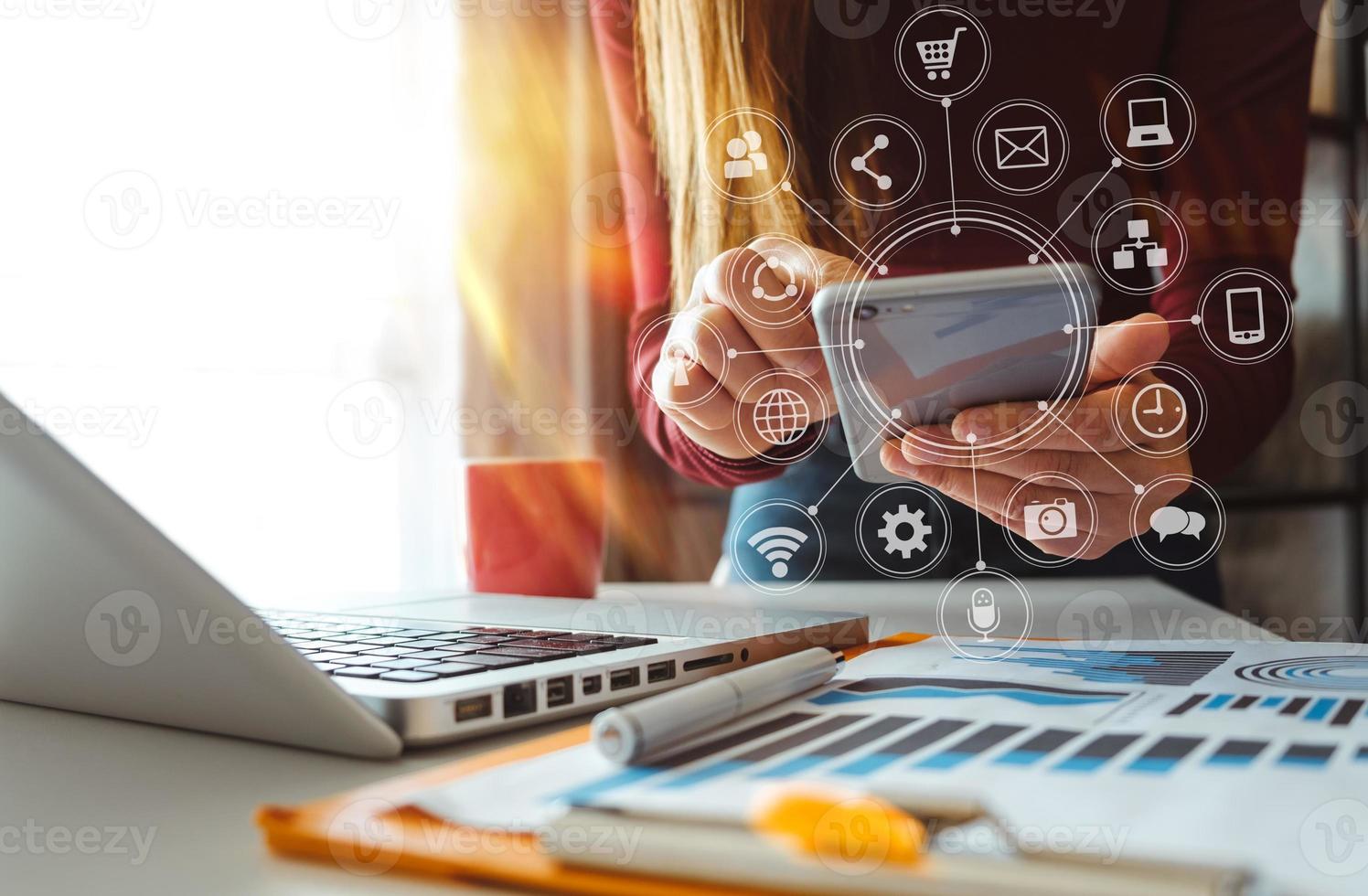 mãos usando o celular no escritório moderno com laptop foto