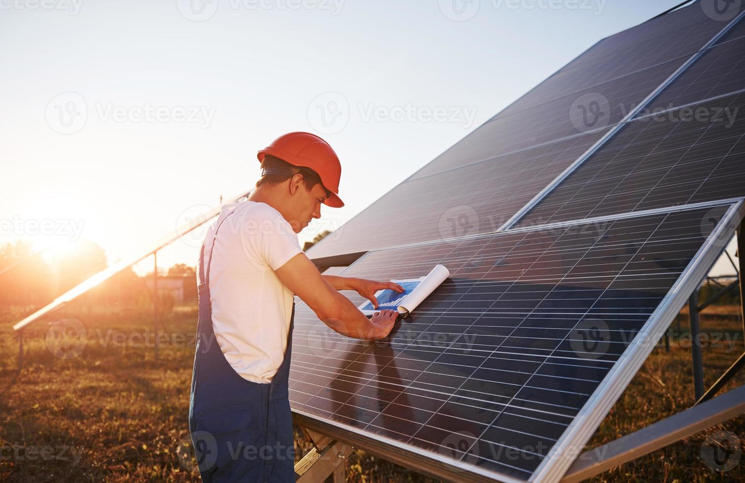 bela luz do sol. trabalhador masculino em uniforme azul ao ar livre com baterias solares foto