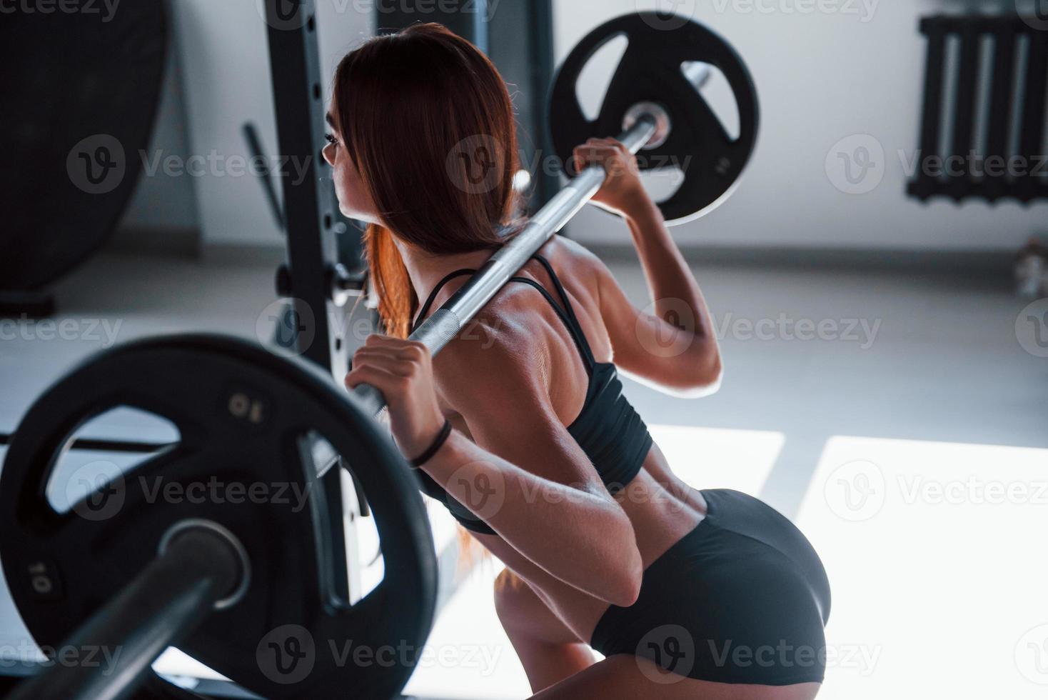 mulher jovem fitness com corpo magro fazendo exercícios usando barra foto