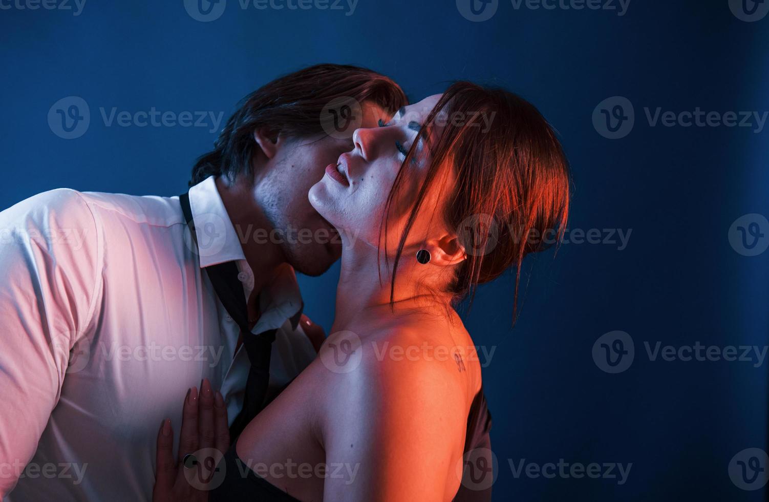 homem bonito com sua namorada gostosa está no estúdio com iluminação neon azul. casal apaixonado um pelo outro foto