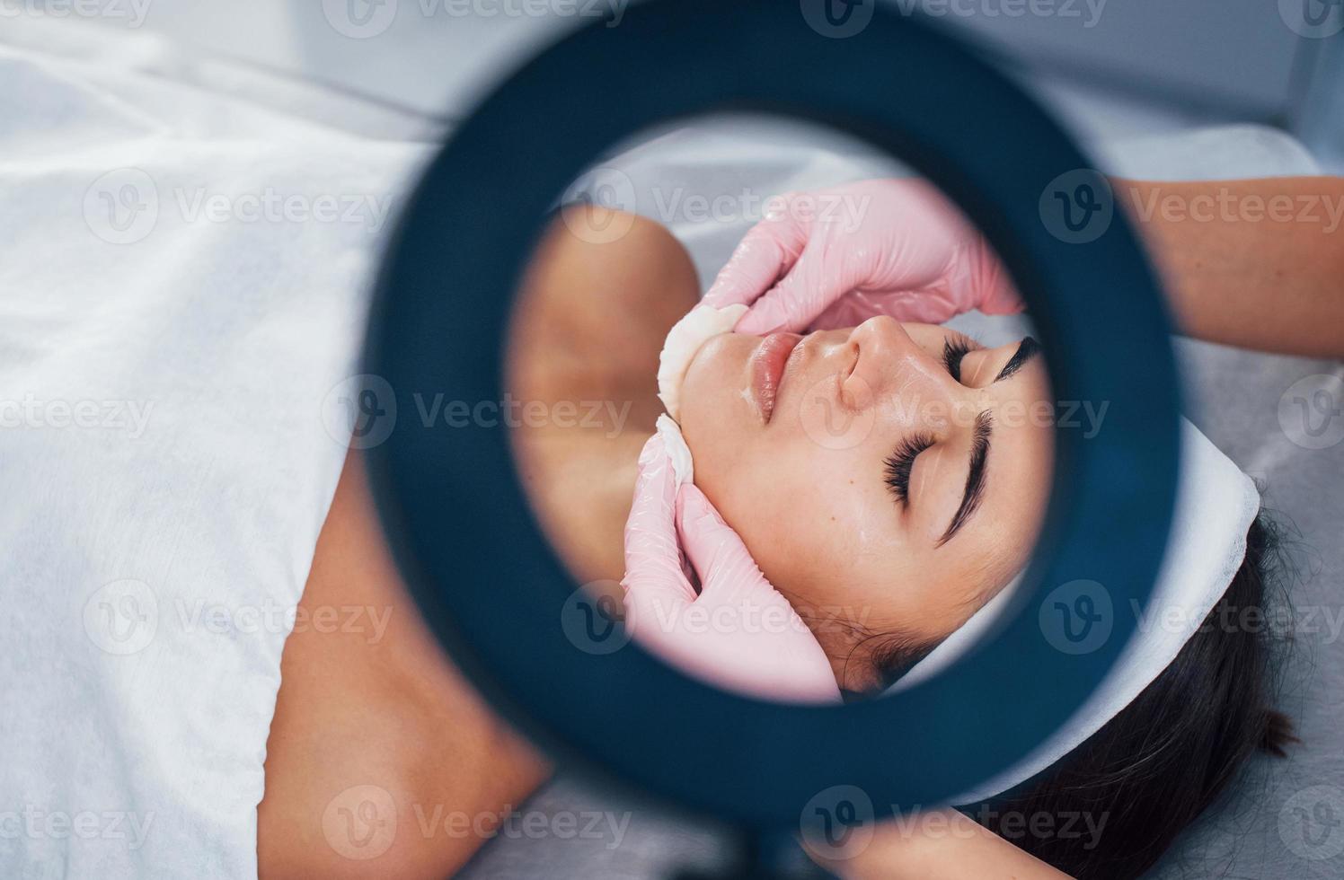 close-up vista da mulher que está deitada no salão spa e tem procedimento de limpeza facial foto