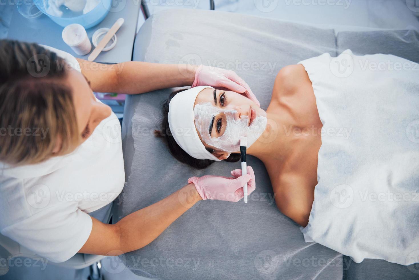 visão aproximada da mulher que está deitada no salão spa e tem procedimento de limpeza facial pela máscara foto