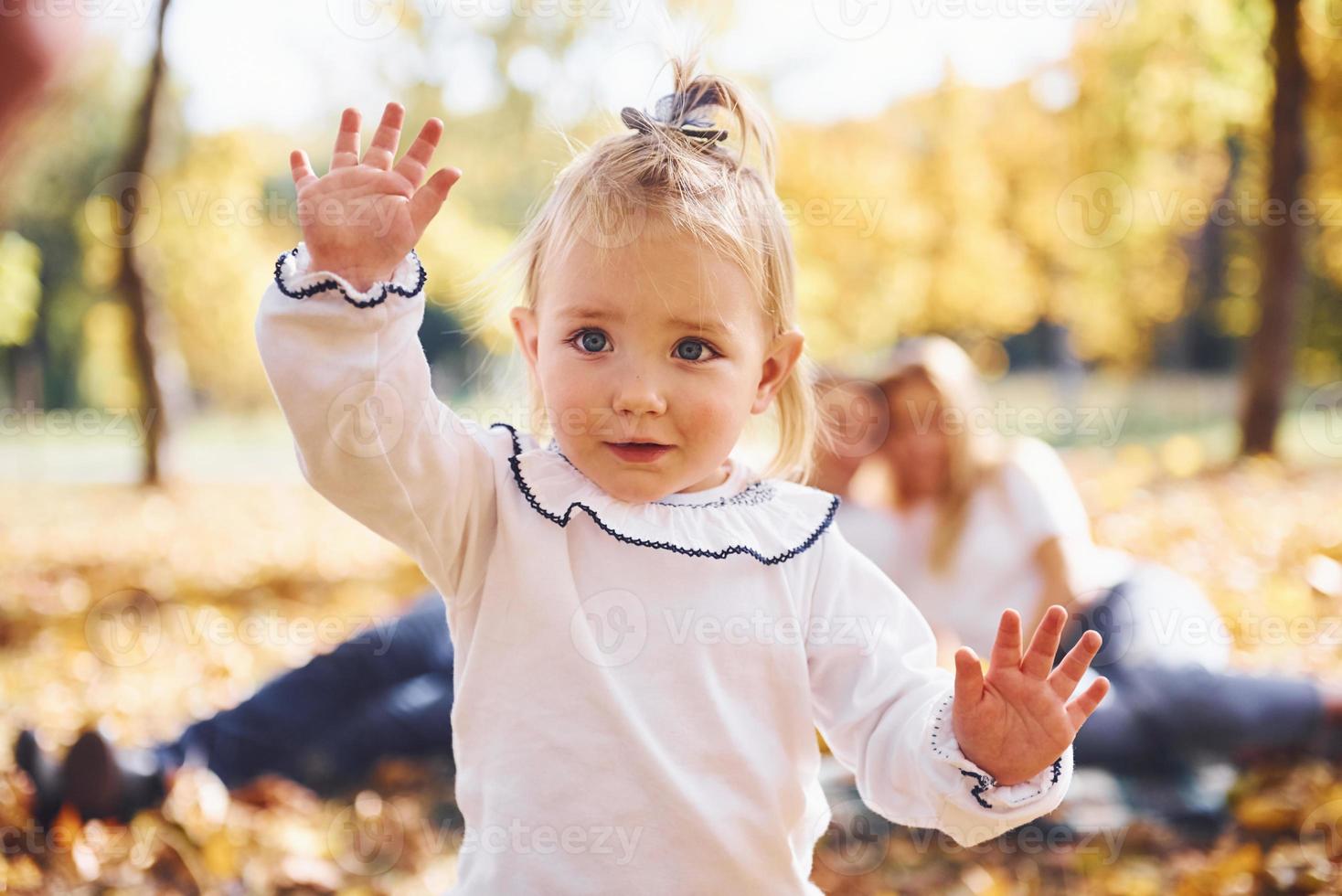 menina bonitinha anda para a câmera. família jovem e alegre descansa em um parque de outono juntos foto