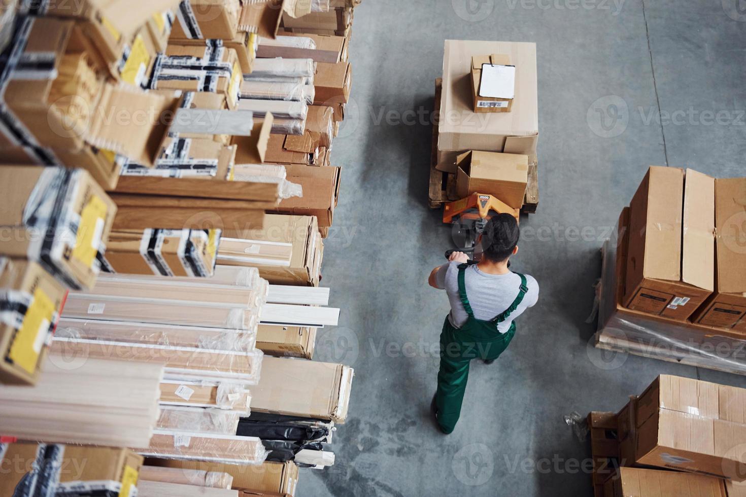 vista superior do trabalhador masculino no armazém com paleteira foto