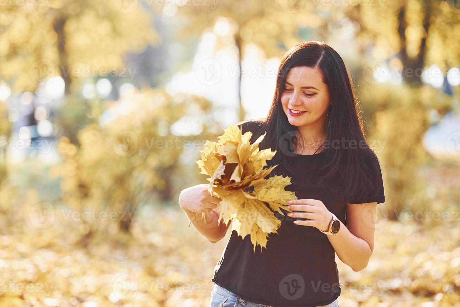 retrato de morena que se diverte com folhas no belo parque outono foto