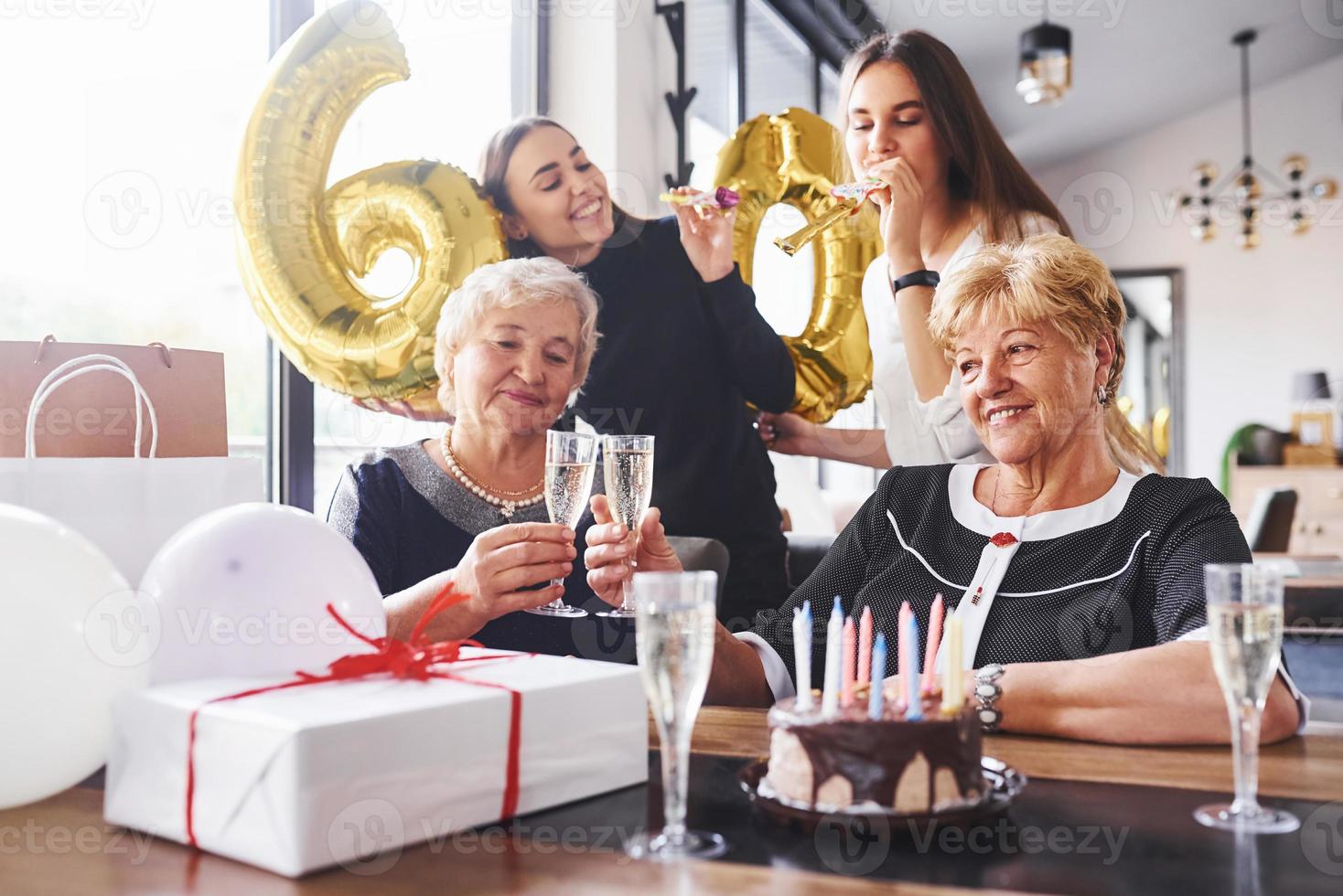 balões com o número 60. mulher sênior com família e amigos comemorando um aniversário dentro de casa foto