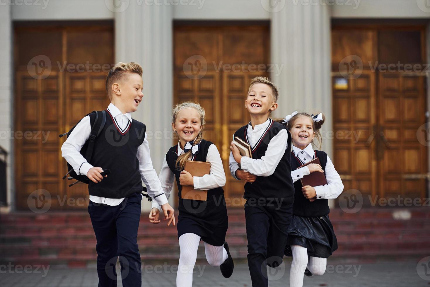 grupo de crianças em uniforme escolar que está correndo ao ar livre juntos foto