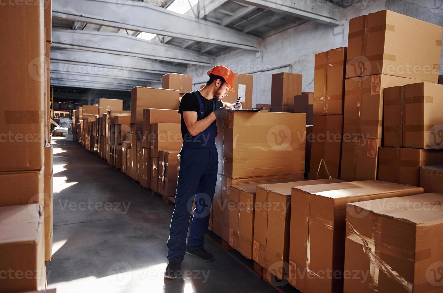 trabalhador de armazenamento de uniforme e bloco de notas nas mãos verifica a produção foto