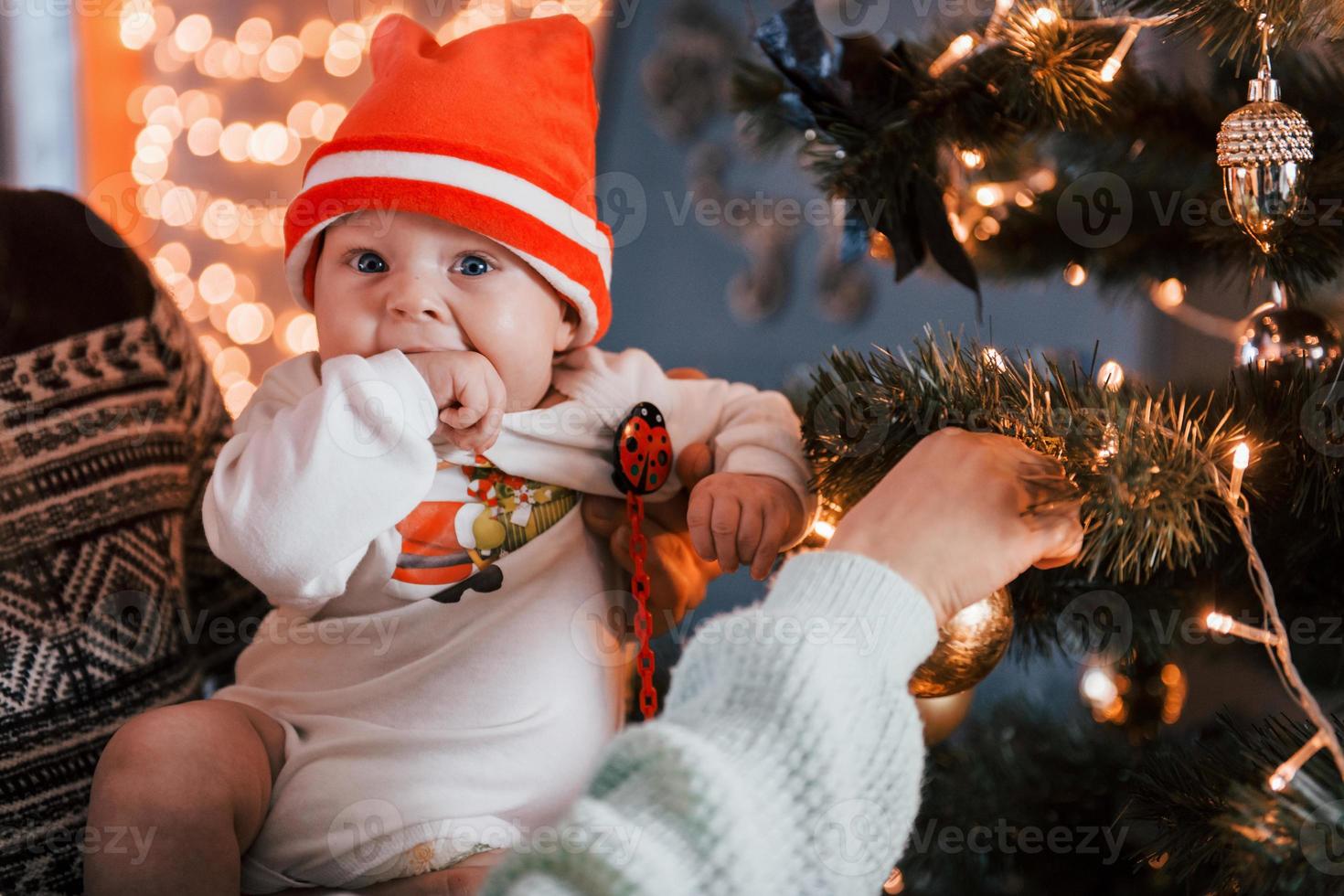 pai e mãe com seu filho decorando árvore juntos no quarto foto