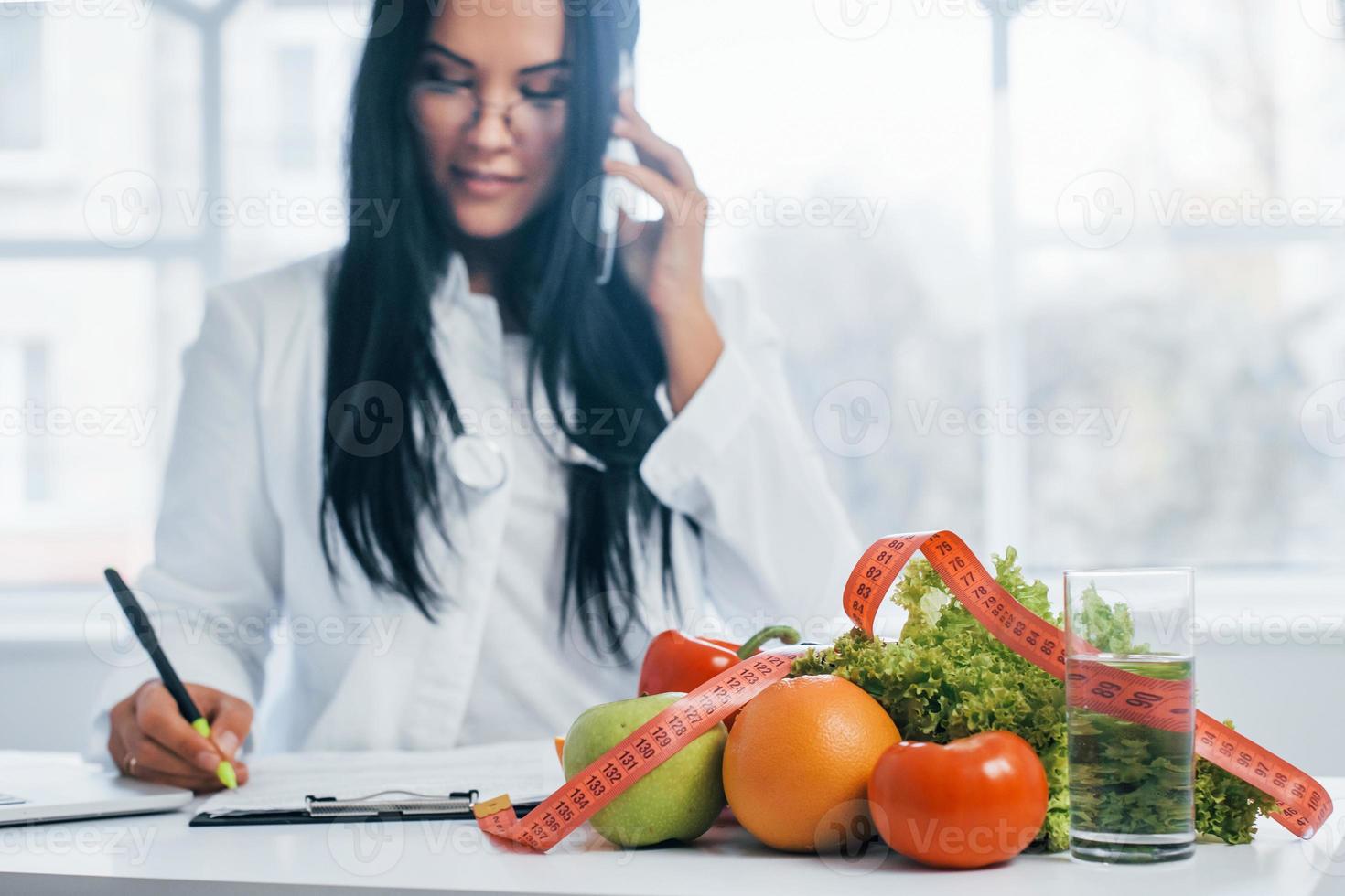 nutricionista feminina em casaco branco sentado dentro de casa no escritório no local de trabalho foto