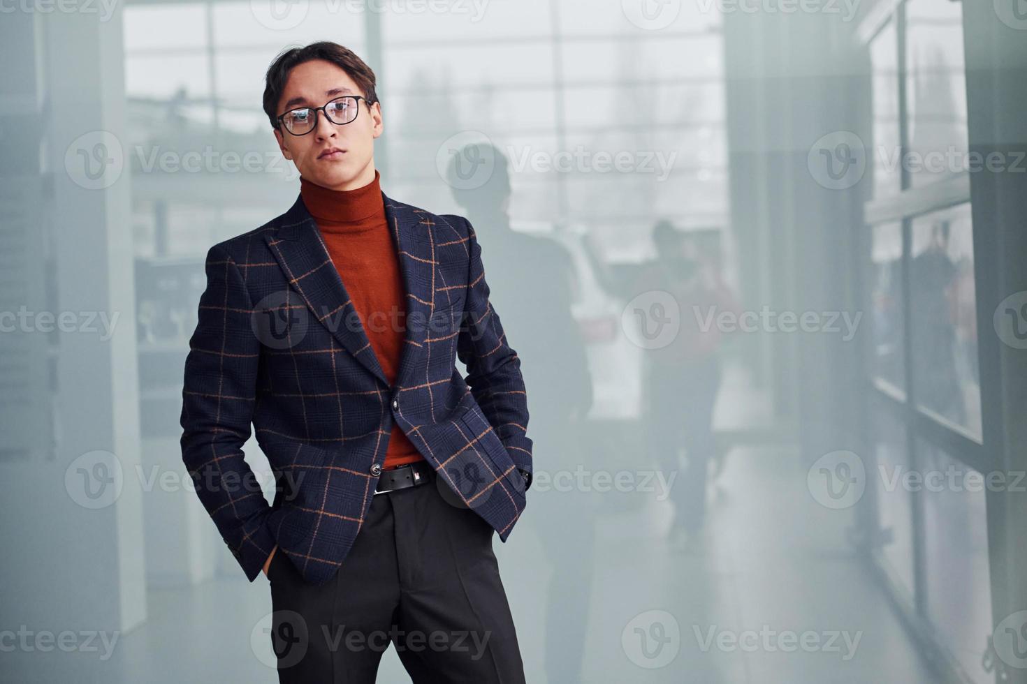 homem de negócios jovem em terno de luxo e roupas formais posando para a câmera dentro de casa foto
