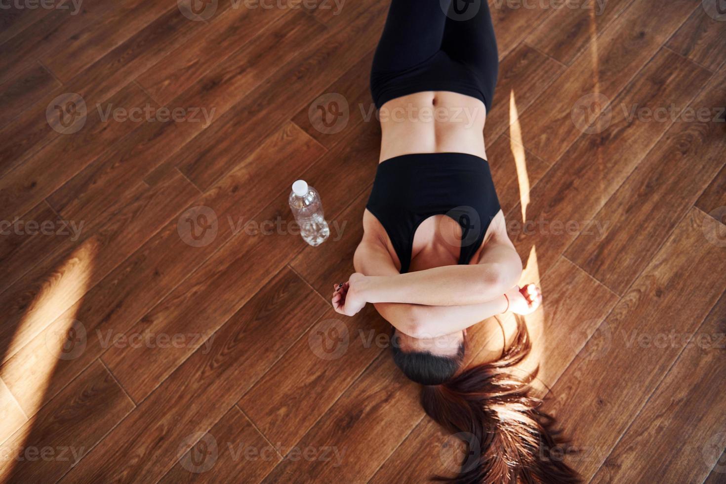 no chão iluminado por feixes de luz. jovem mulher desportiva em sportswear descansando foto