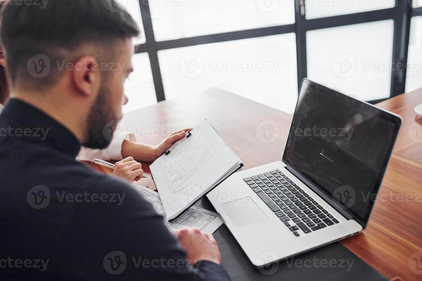 mulher e homem em roupas formais trabalhando juntos dentro de casa no escritório por mesa com documentos foto