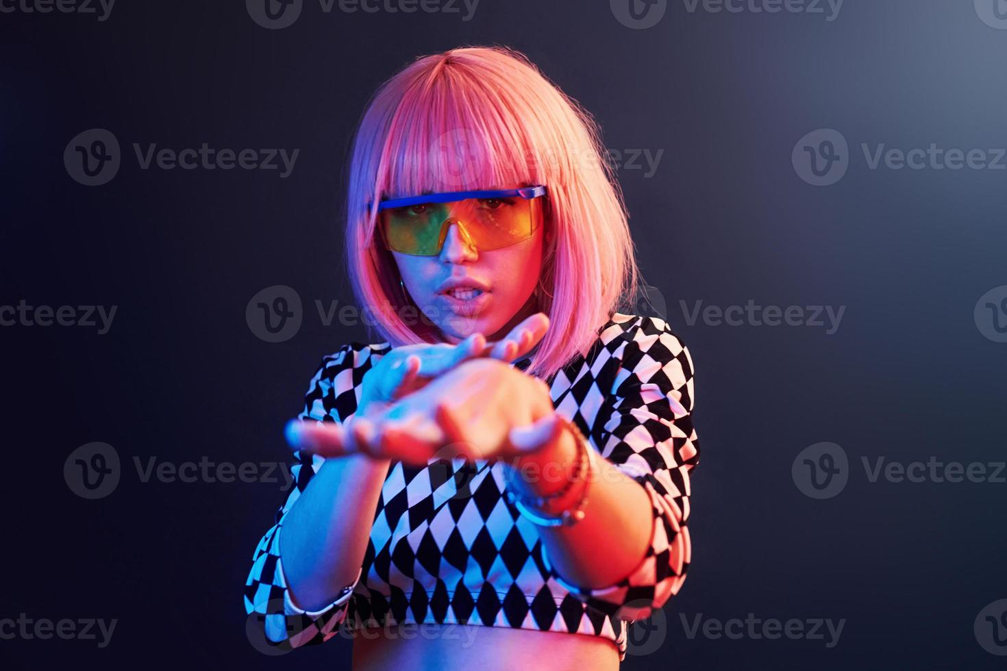 retrato de jovem com cabelo loiro em óculos em néon vermelho e azul no estúdio foto