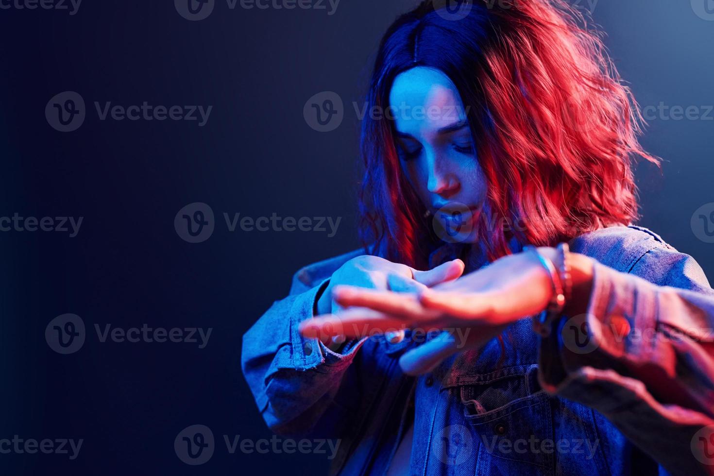 retrato de uma jovem com cabelos cacheados que dança em neon vermelho e azul no estúdio foto