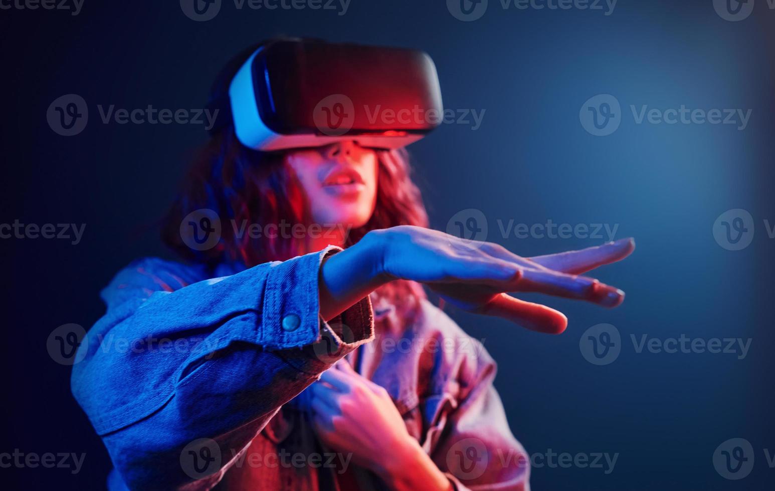 expressão facial de jovem com óculos de realidade virtual na cabeça em néon vermelho e azul no estúdio foto