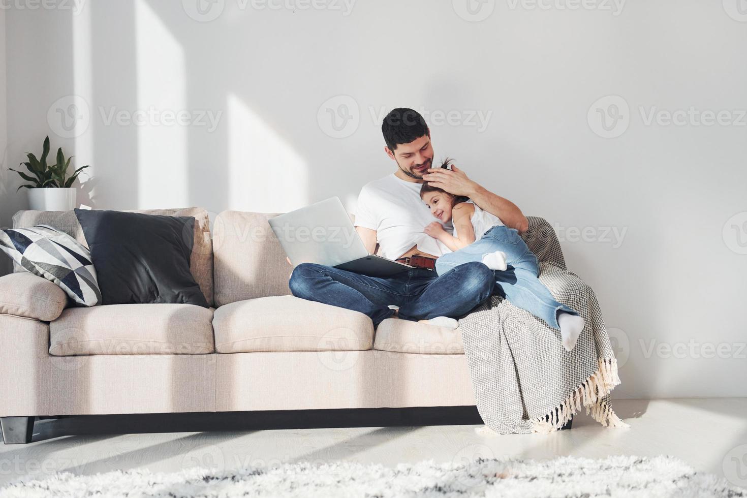 pai feliz com sua filha passando tempo livre com laptop em casa juntos foto