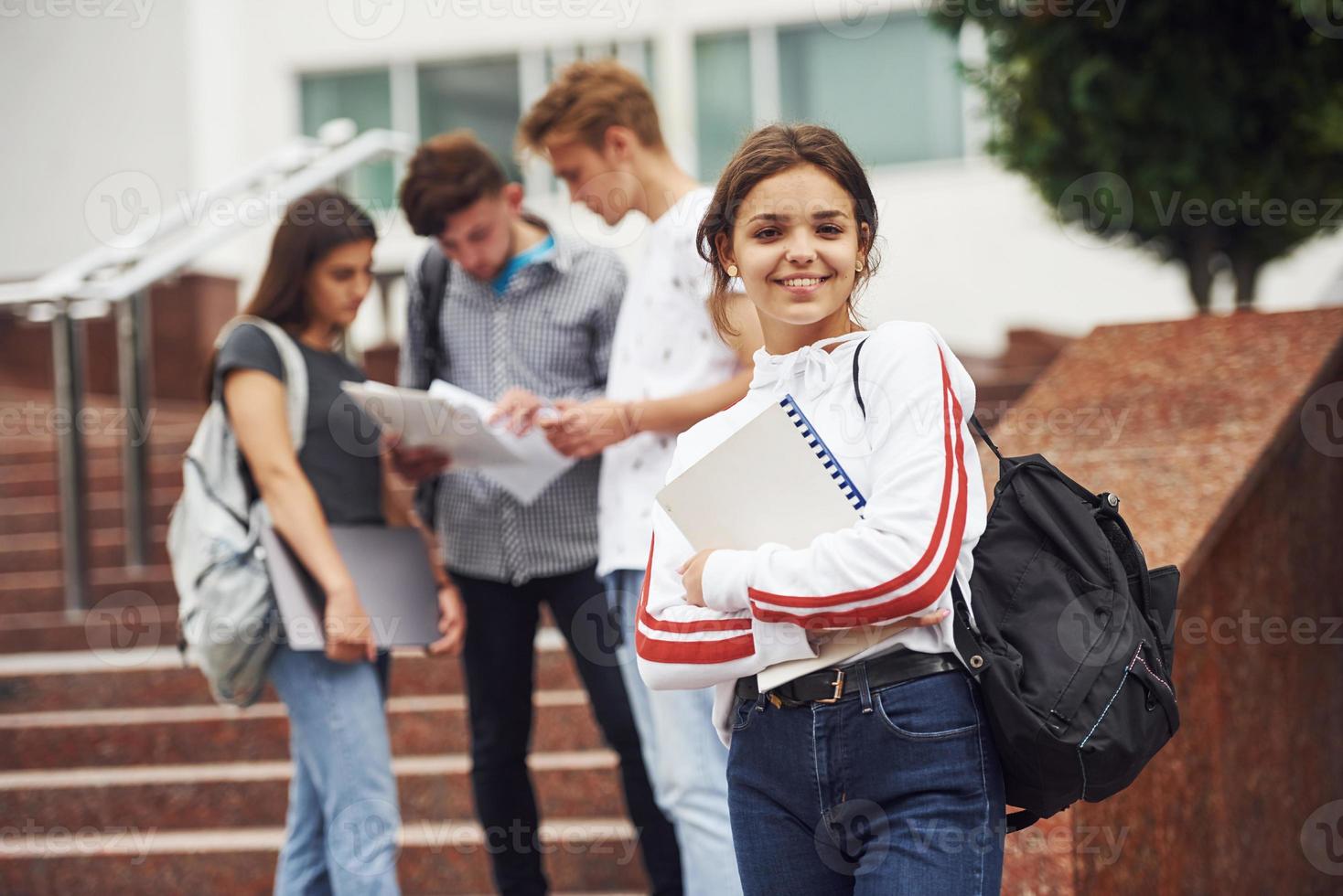 linda garota adolescente. grupo de jovens estudantes em roupas casuais perto da universidade durante o dia foto