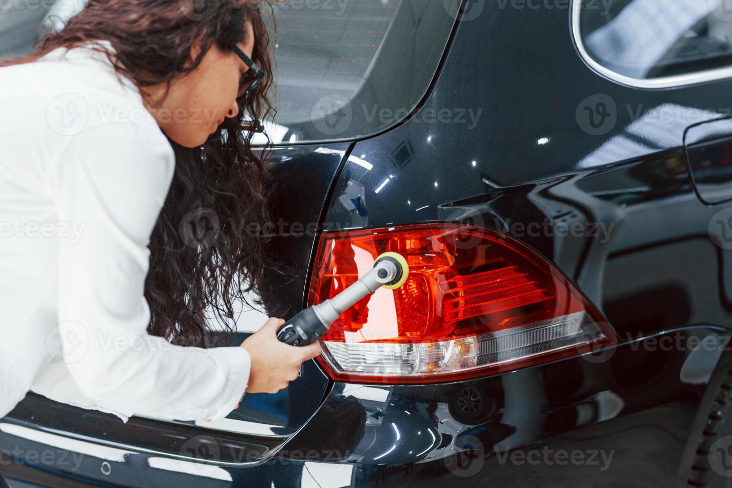 mulher com equipamento de limpeza automóvel moderno. concepção de serviço foto