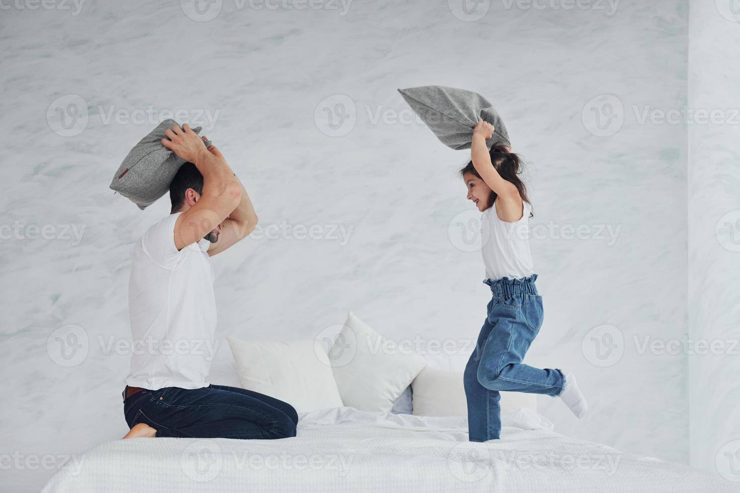 pai feliz com sua filha brincando de luta de almofadas no tempo livre em casa juntos foto