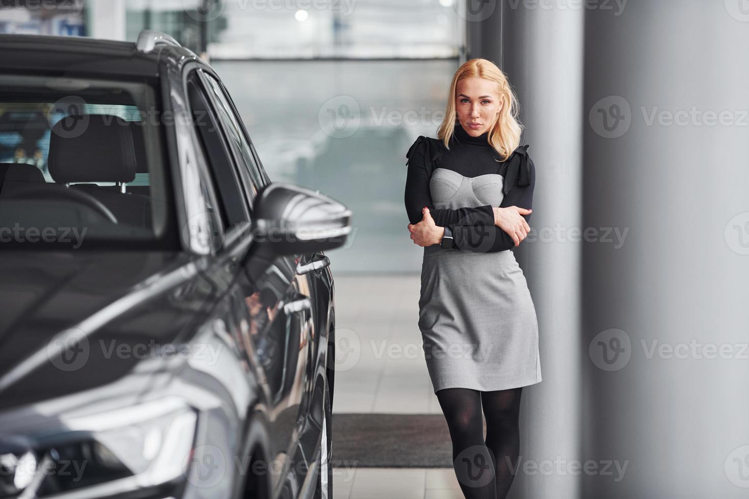 loira linda em roupas elegantes em pé perto de carro novo e moderno foto