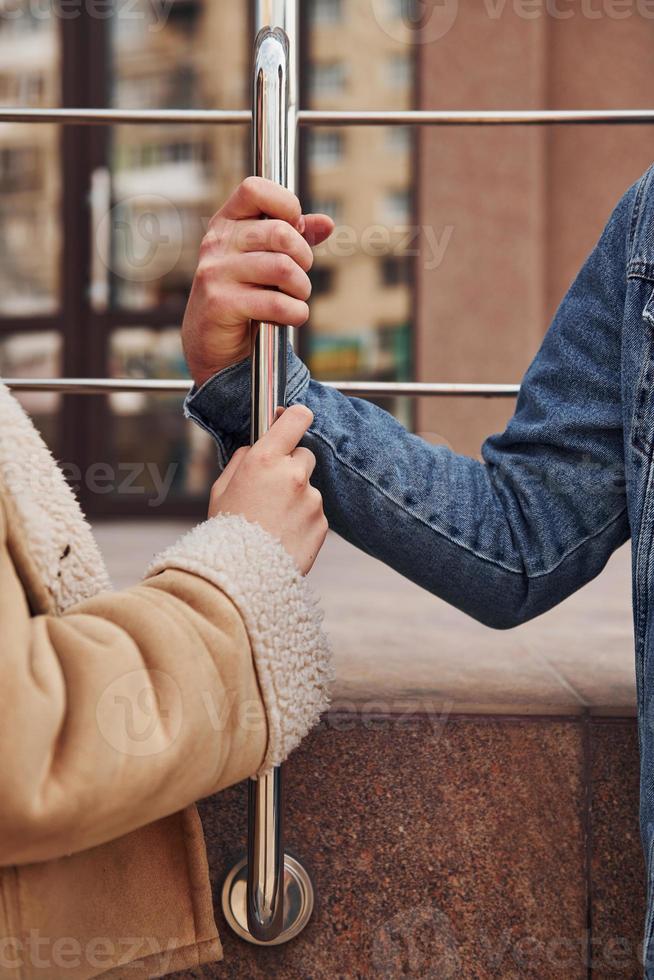 visão aproximada das mãos da mulher e do homem que seguram o corrimão prateado em tempo de quarentena foto