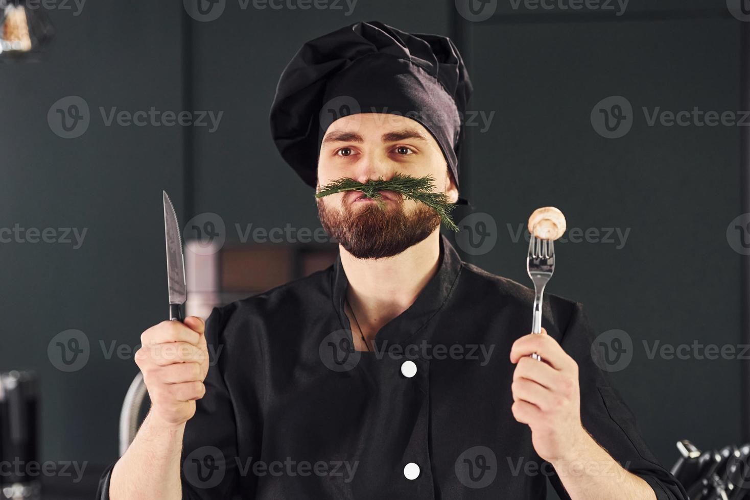 retrato de cozinheiro profissional jovem chef de uniforme que posando para a câmera na cozinha foto