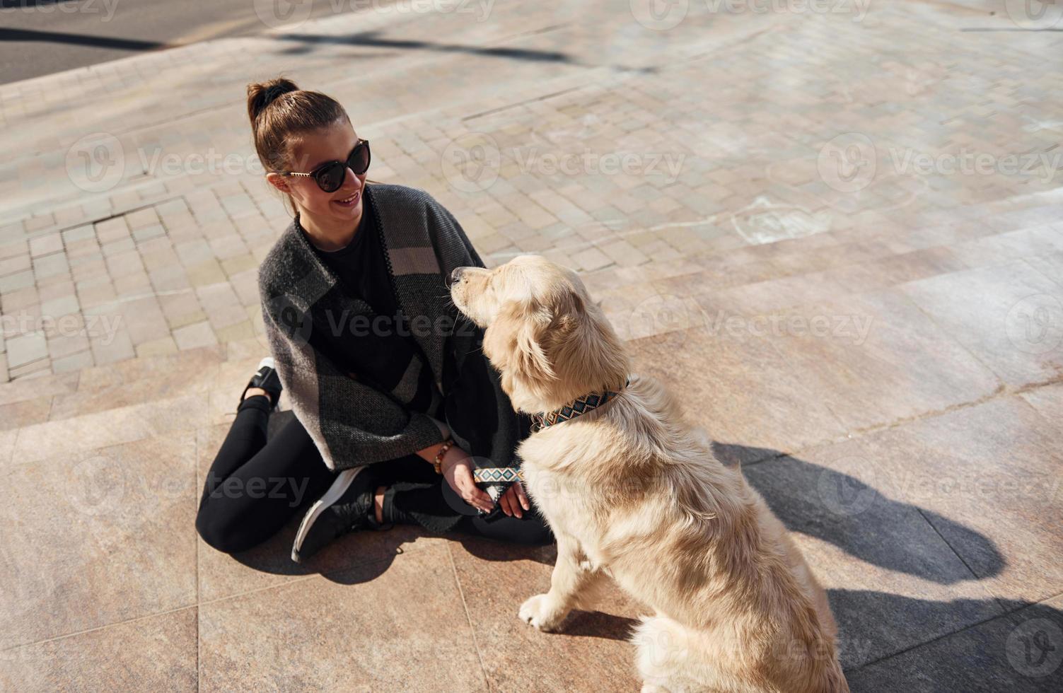 jovem mulher positiva se diverte com seu cachorro quando caminha ao ar livre foto