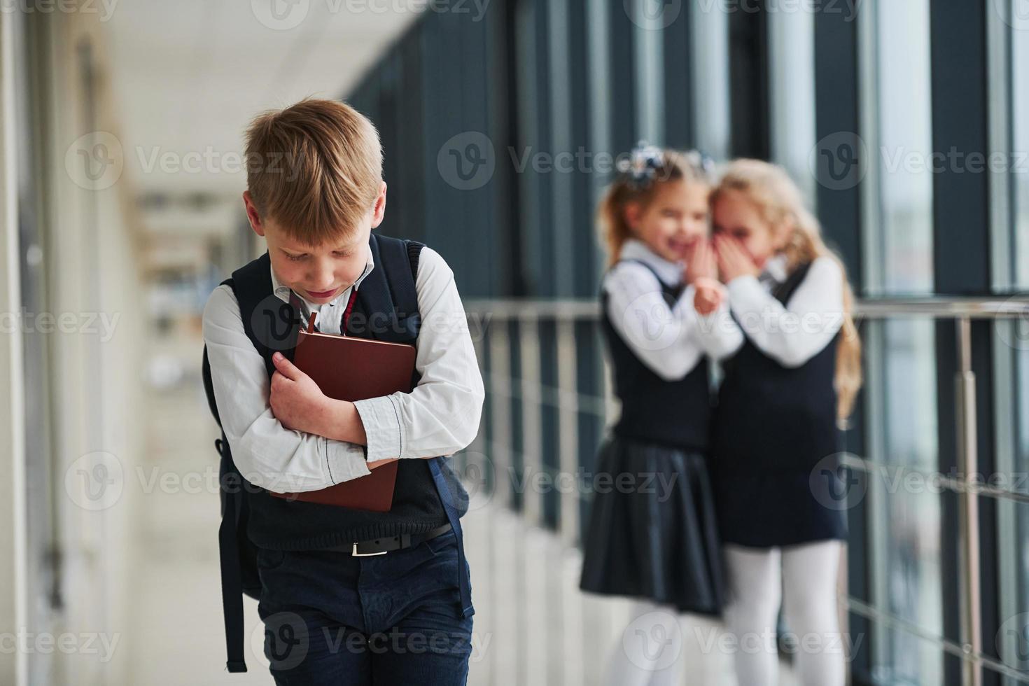 garotinho fica intimidado. concepção de assédio. crianças da escola de uniforme juntos no corredor foto