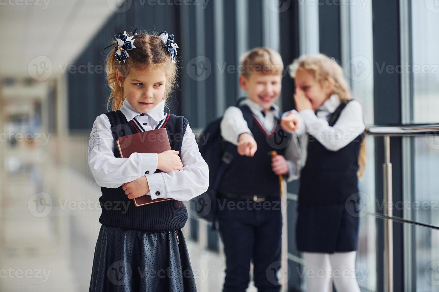 menina sofre bullying. concepção de assédio. crianças da escola de uniforme juntos no corredor foto