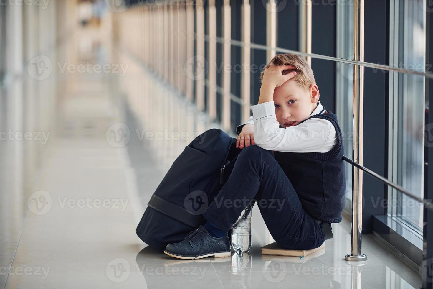 menino de uniforme sentado sozinho com sentimento triste na escola. concepção de assédio foto