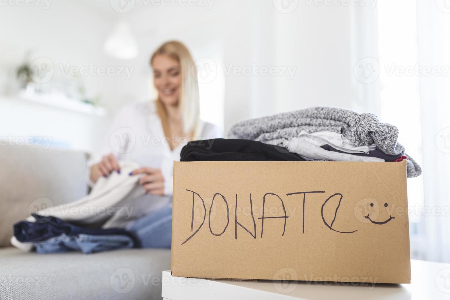 mulher embalando roupas em caixa de doação na sala de estar. menina coloca em uma caixa com itens de doações. voluntariado. mulher participando de caridade e segurando caixa de doação foto