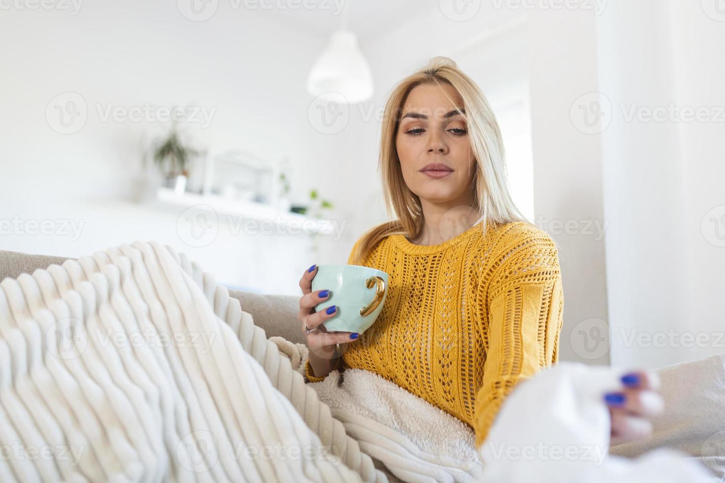 mulher doente coberta com um cobertor deitada na cama com febre alta e gripe, descansando na sala de estar. ela está exausta e sofrendo de coronavírus. mulher doente com nariz escorrendo, deitada na cama. foto