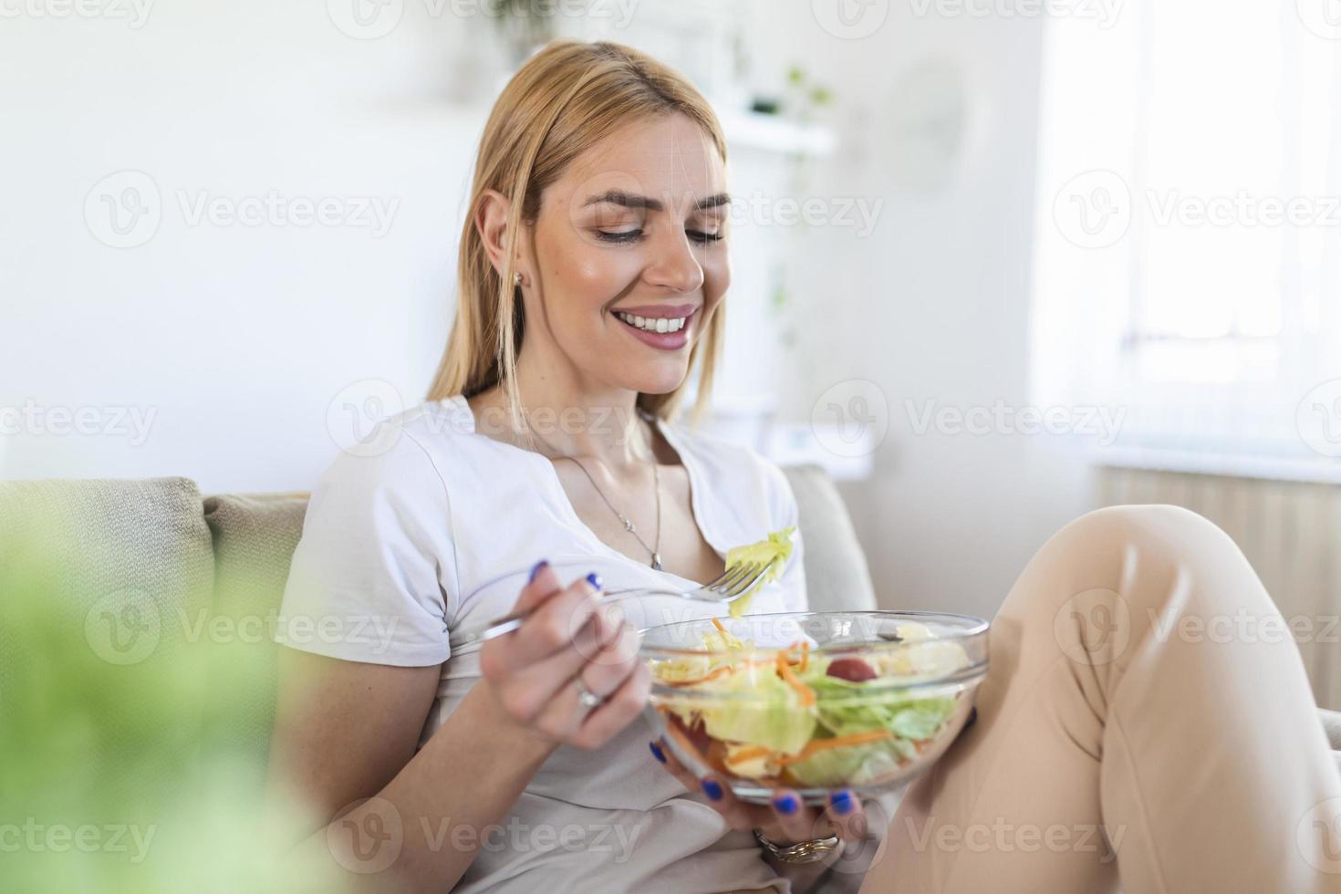 retrato de mulher sorridente caucasiana atraente comendo salada. mulher comendo salada saudável com tomate cereja dentro de casa estilo de vida saudável foto