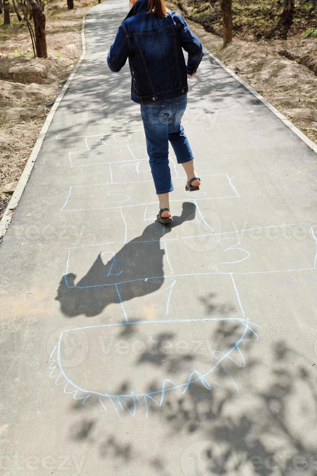 menina pulando na amarelinha no beco urbano foto