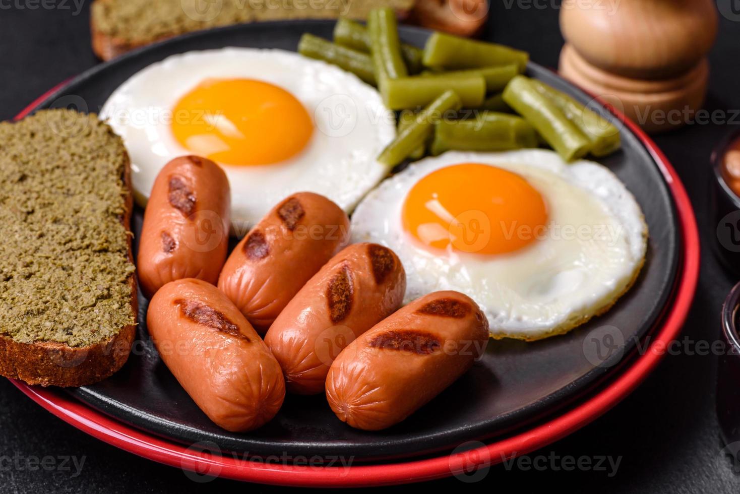 saboroso café da manhã inglês com ovos fritos, feijão, aspargos, salsichas com especiarias e ervas foto