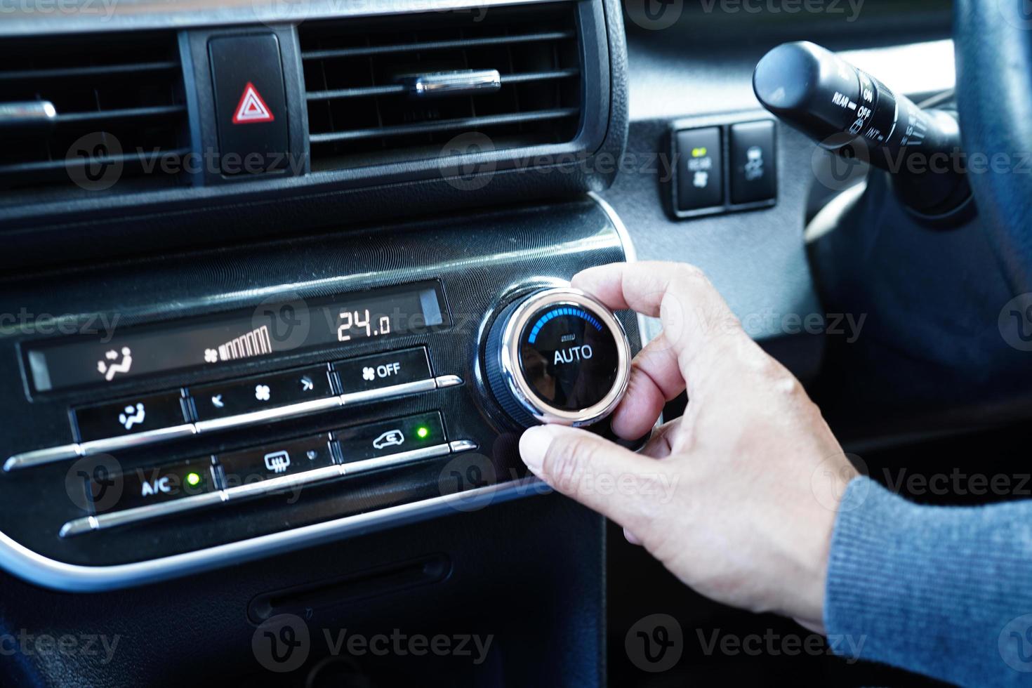 motorista de mulher asiática ajustando o sistema de ar condicionado de controle de temperatura no carro. foto