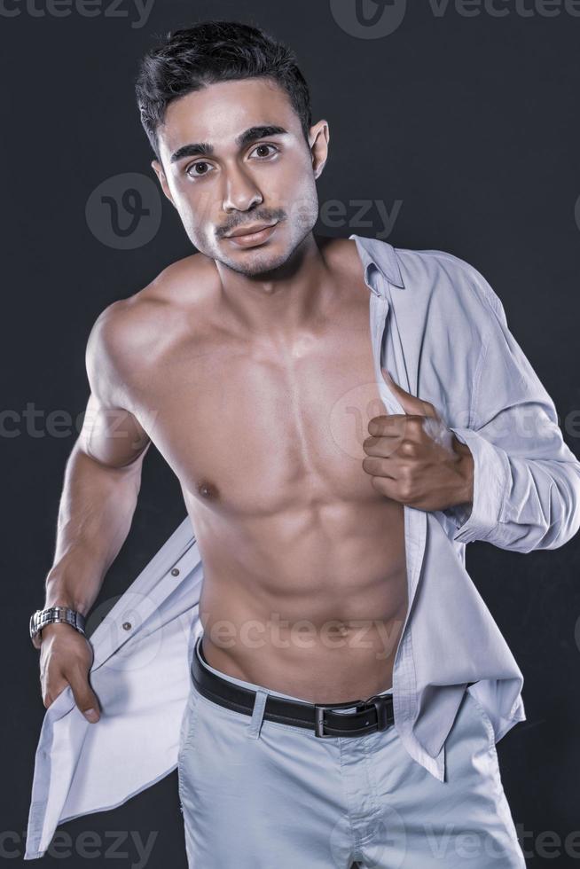 belo modelo masculino árabe com corpo perfeito posando no estúdio. retrato de um modelo masculino atlético posando em fundo escuro no estúdio. conceito de moda. foto