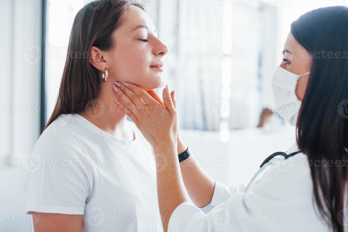 verificando gânglios linfáticos e garganta. jovem tem uma visita com médica na clínica moderna foto