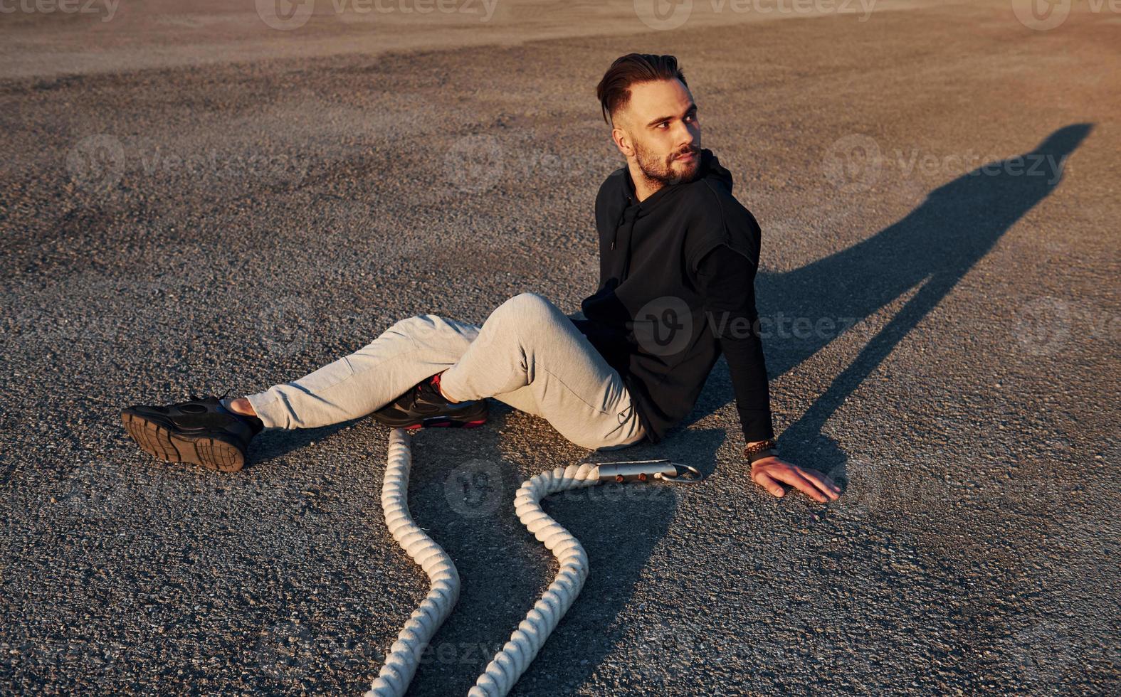 homem em roupas esportivas sentado na estrada ao entardecer com cordas e descansando foto