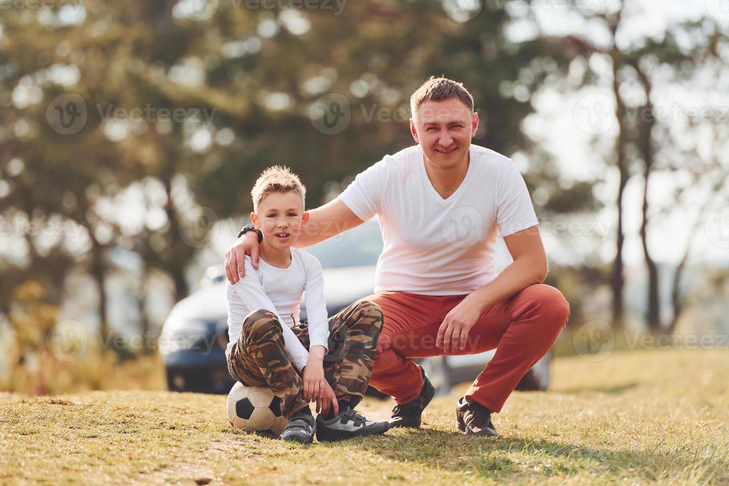 jogando futebol. pai com seu filho passando o fim de semana juntos ao ar livre perto da floresta durante o dia foto