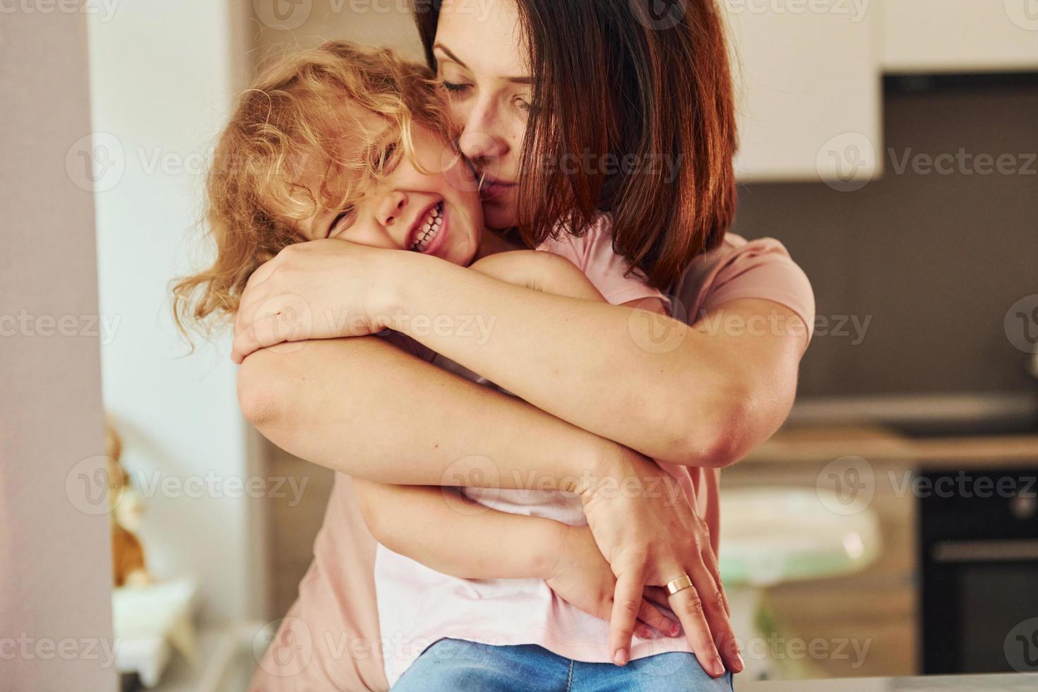 na cozinha. jovem mãe com sua filha em roupas casuais juntos dentro de casa em casa foto