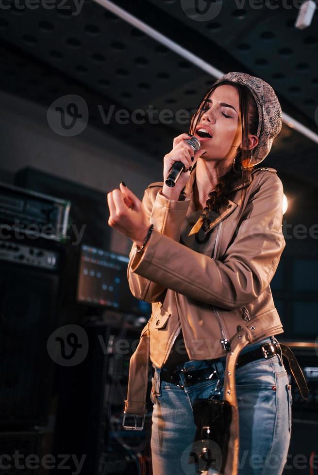 jovem bela cantora ensaiando em um estúdio de gravação foto