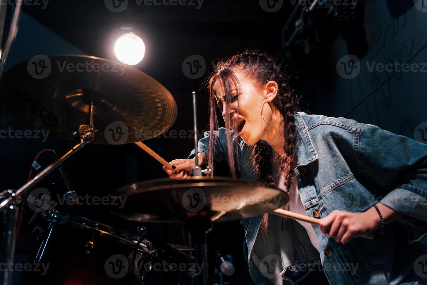 toca bateria. jovem bela artista feminina ensaiando em um estúdio de gravação foto