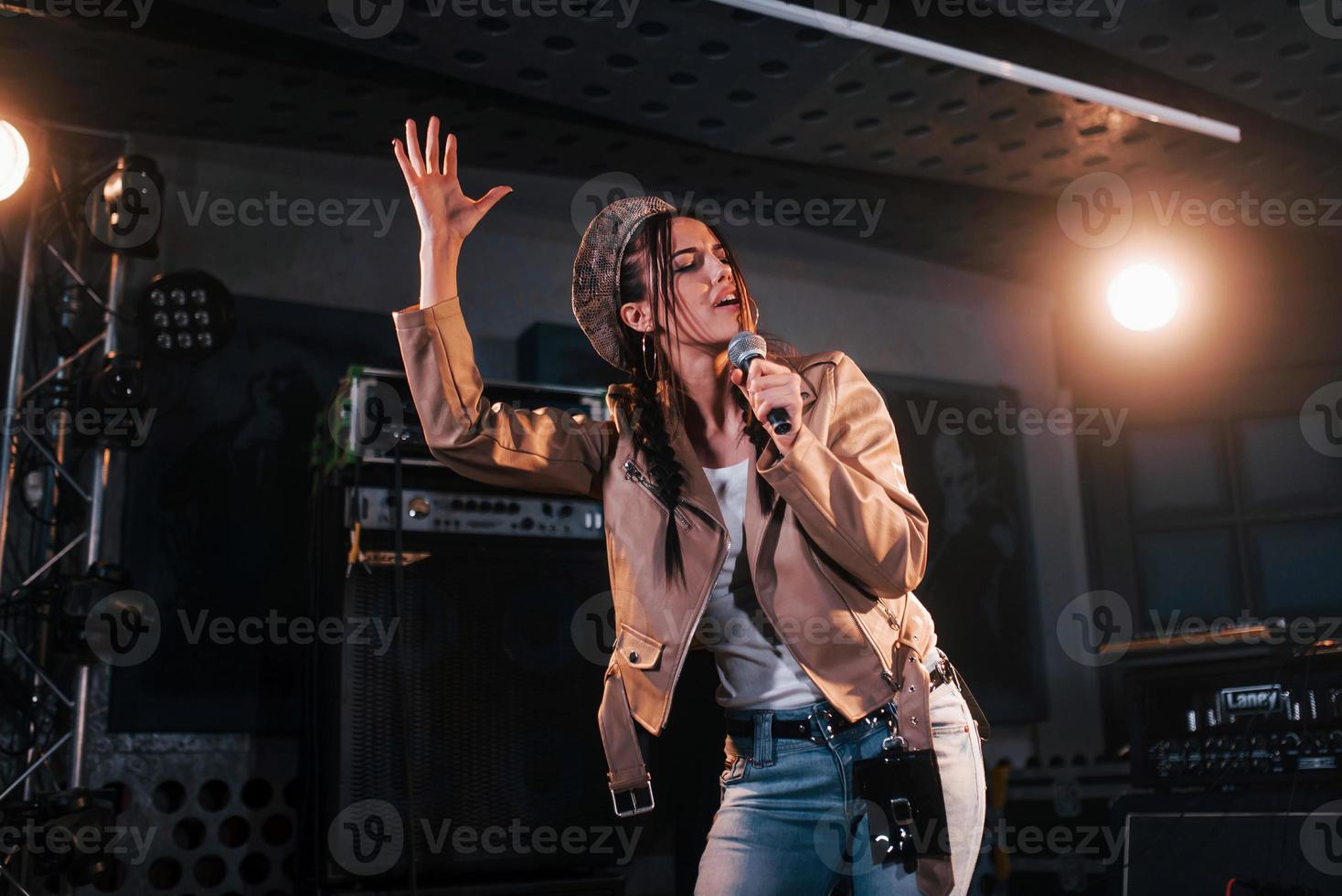 jovem bela cantora ensaiando em um estúdio de gravação foto