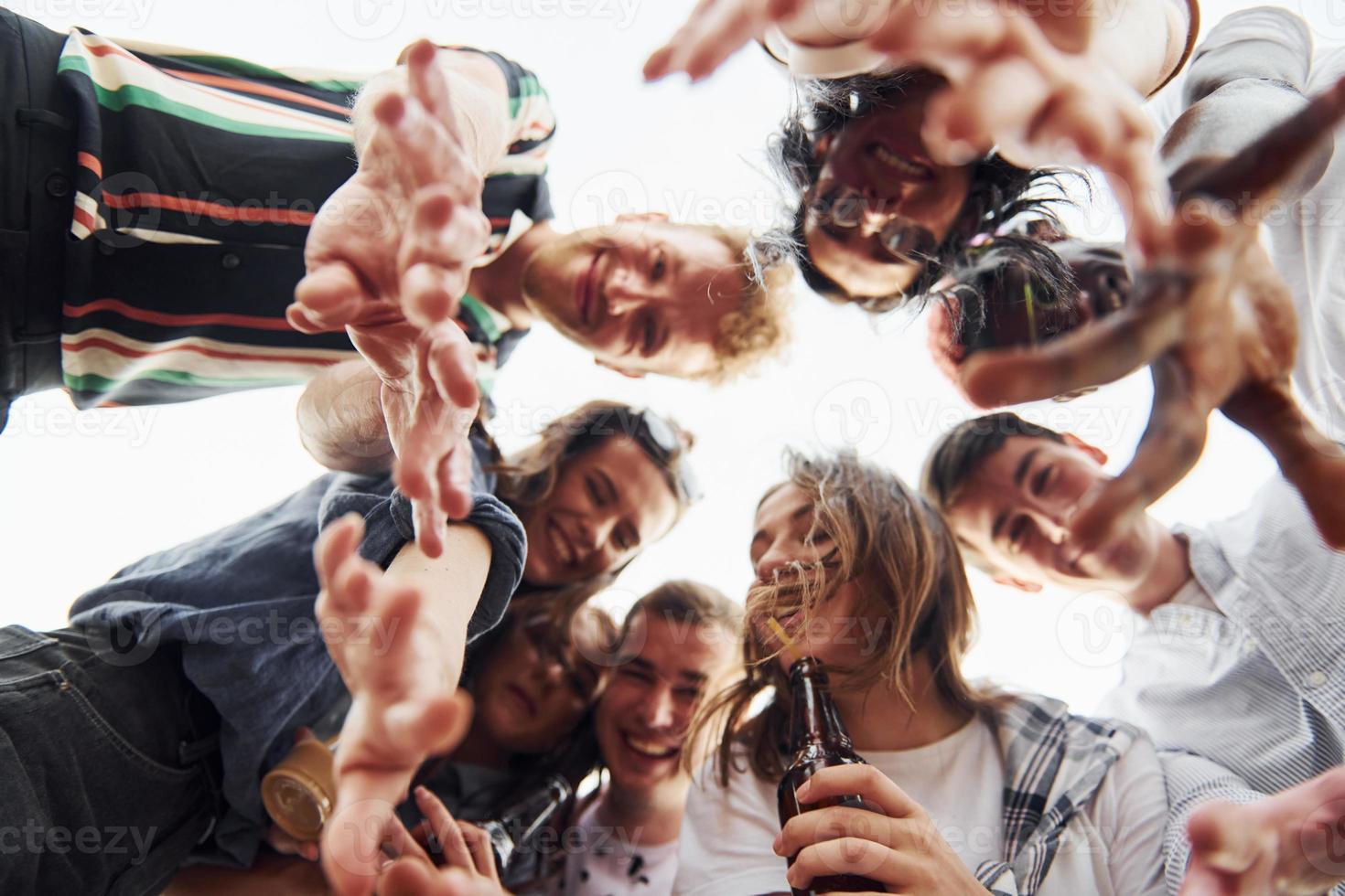 olhando para baixo. vista de baixo. grupo de jovens em roupas casuais faz uma festa no telhado juntos durante o dia foto