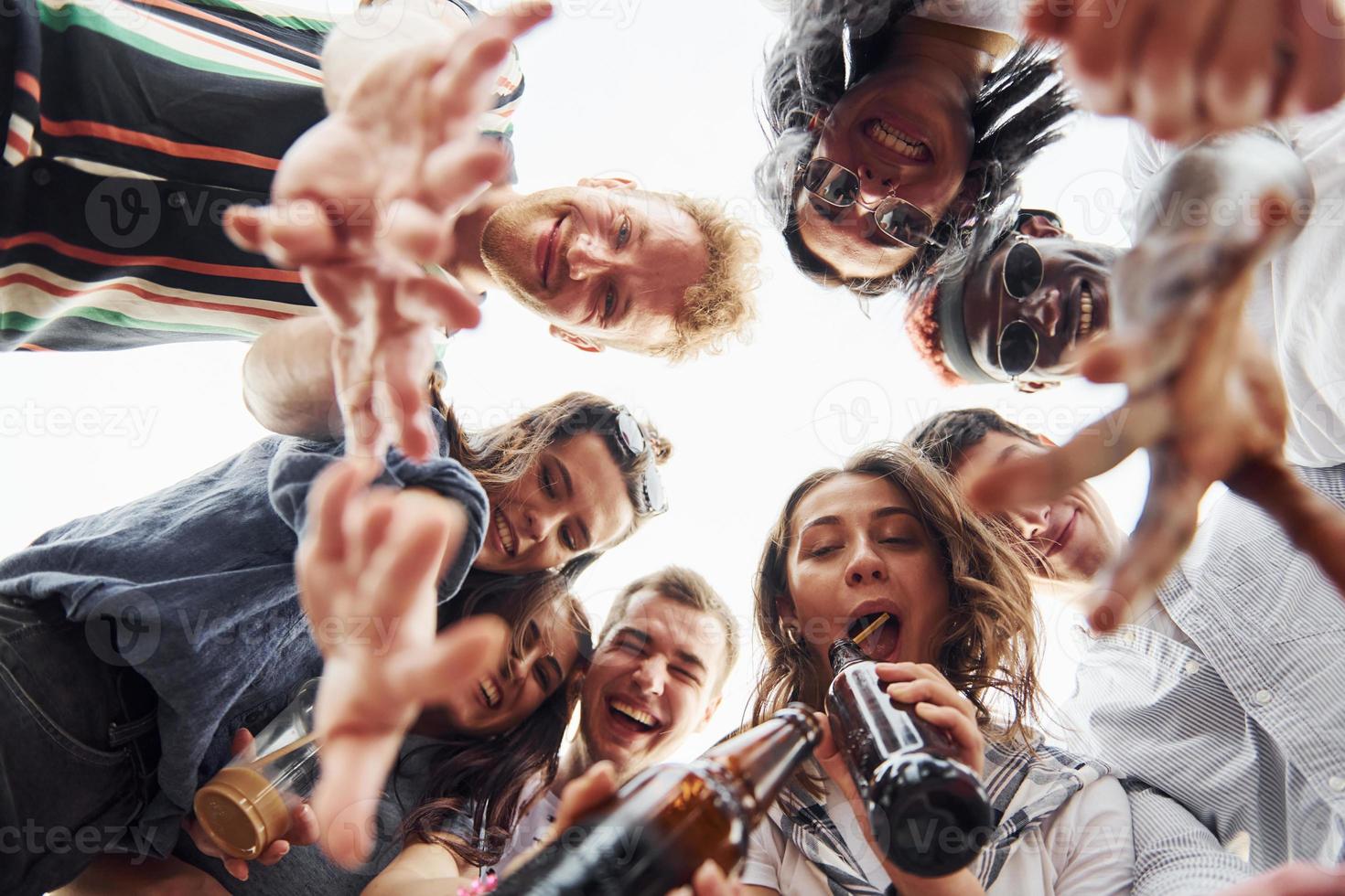 olhando para baixo. vista de baixo. grupo de jovens em roupas casuais faz uma festa no telhado juntos durante o dia foto