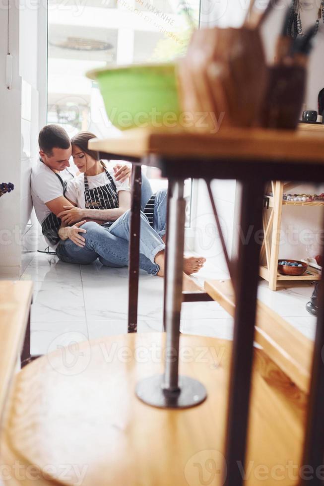 fazendo uma pausa e sentando no chão. com o namorado ou marido. jovem ceramista feminina dentro de casa com produto de argila artesanal. concepção de cerâmica foto