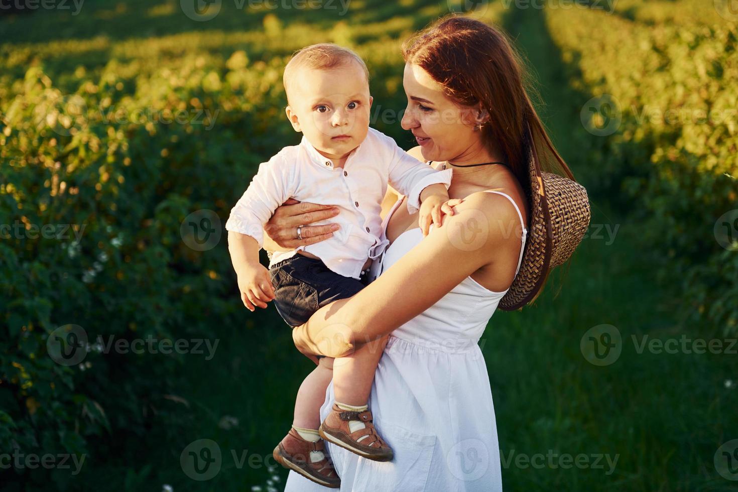 mãe positiva com seu filho passando o tempo livre no campo no dia ensolarado do verão foto