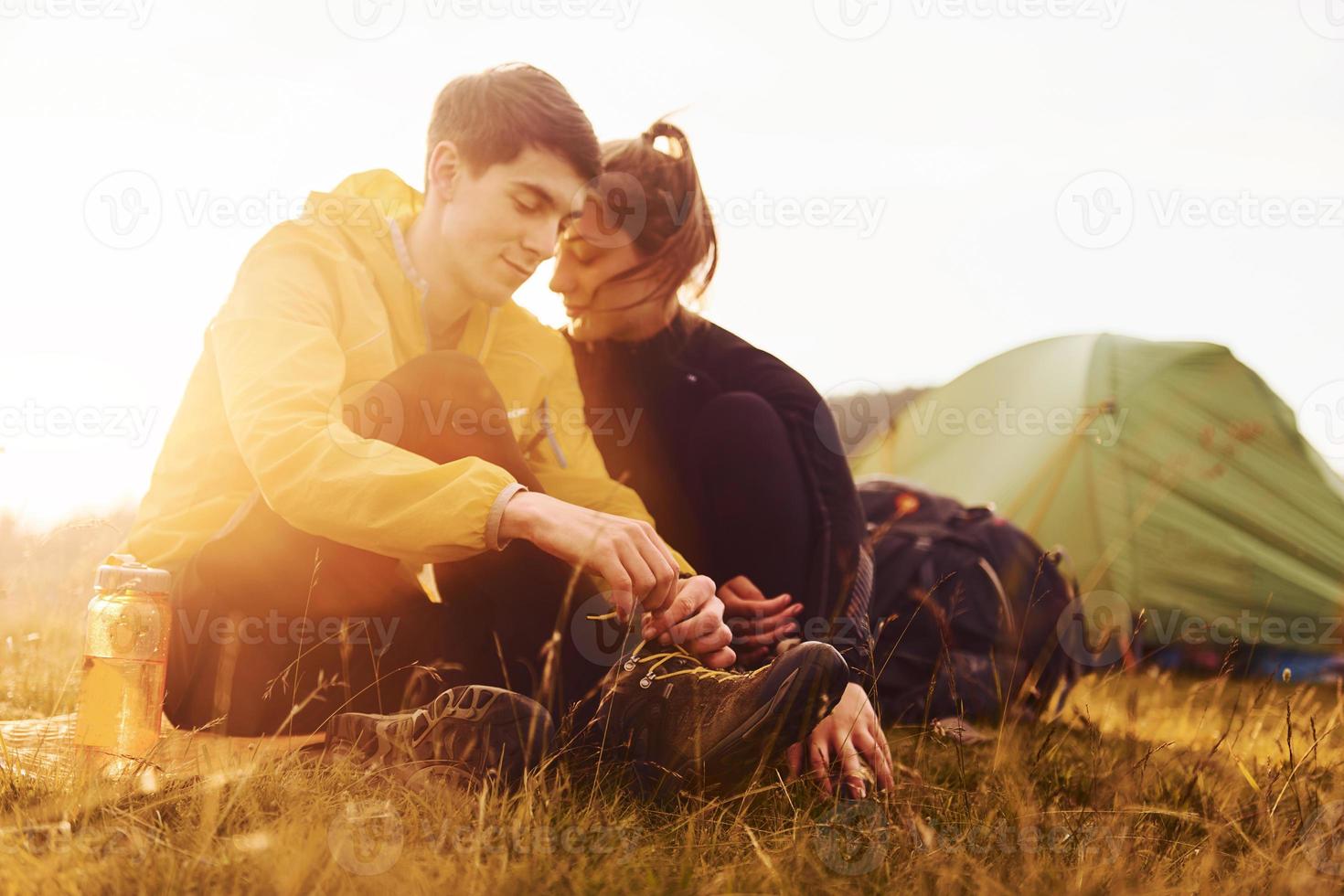 jovem casal adorável sentado perto da tenda ao ar livre durante o dia. bela luz do sol foto